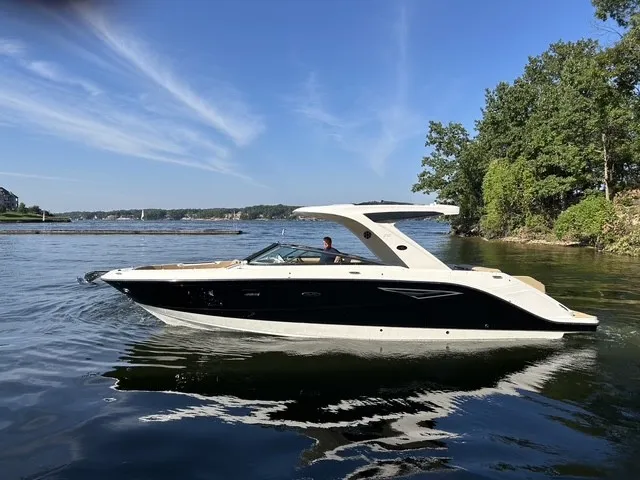 Slide: The Image of A sleek 2027 Sea Ray SLX 310 boat cruising on calm waters, surrounded by trees. - 1