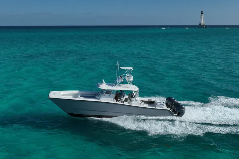 Slide: The Image of 2024 Freeman 42 boat cruising on turquoise ocean near a distant lighthouse. - 17