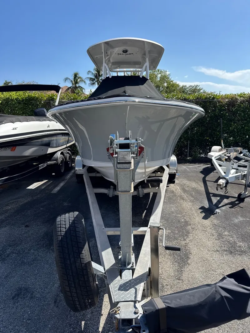 Slide: The Image of A 2022 Sea Hunt Ultra 234 CC boat on a trailer, surrounded by other boats. - 2