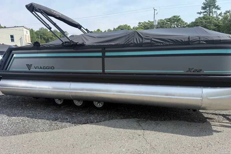 Slide: The Image of 2027 Viaggio X22U pontoon boat with cover, parked on gravel. - 30