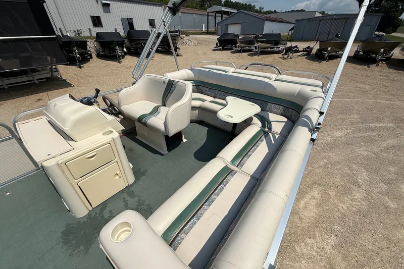 Slide: The Image of 1998 Premier SunSation 250 pontoon boat with spacious seating and helm, parked outdoors. - 15