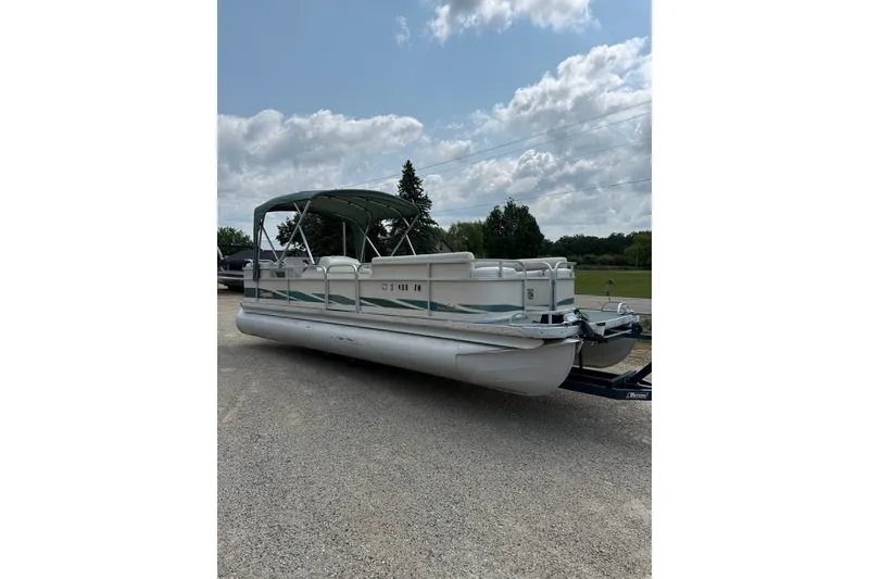The Image of 1998 Premier SunSation 250 pontoon boat on trailer under cloudy sky. - 1