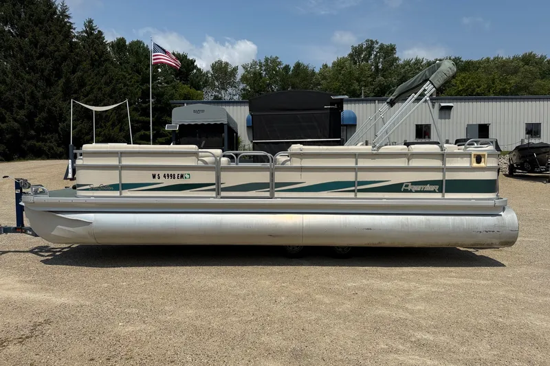 Slide: The Image of 1998 Premier SunSation 250 pontoon boat parked on gravel lot with American flag. - 17