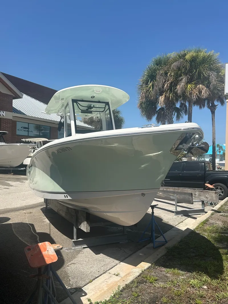 Slide: The Image of A 2025 Sea Hunt Ultra 255SE boat on a trailer in a sunny harbor setting. - 2