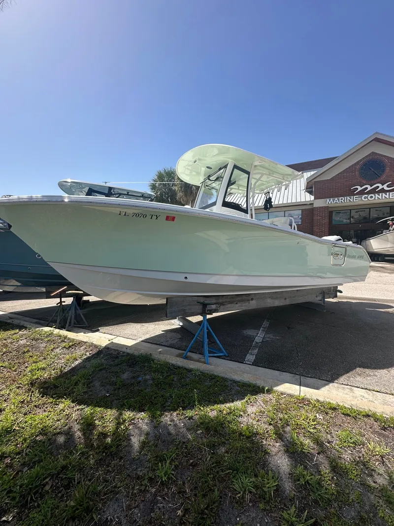The Image of A 2025 Sea Hunt Ultra 255SE boat is parked on a lot. It features a light green canopy. - 1