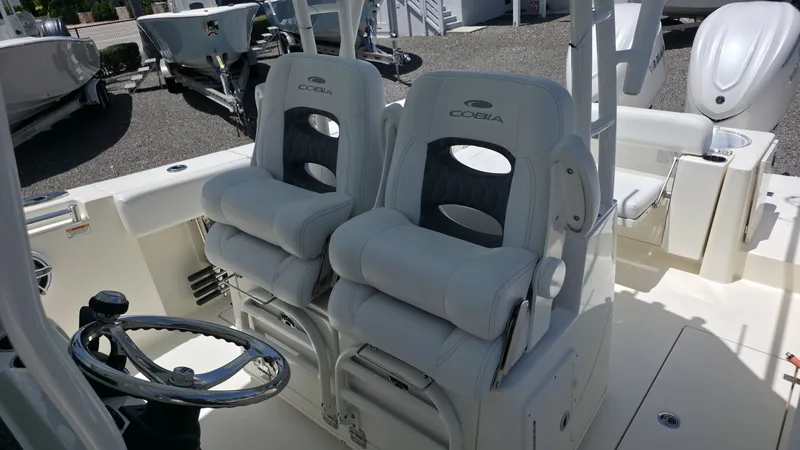 Slide: The Image of Two luxurious, cushioned seats on a Cobia 301 Center Console boat, with a sleek helm station. - 9