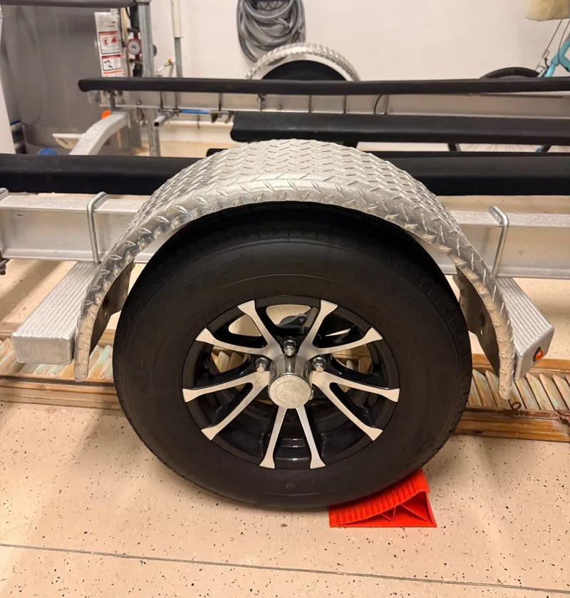 Slide: The Image of A boat trailer with a black wheel and a silver metal fender. - 21