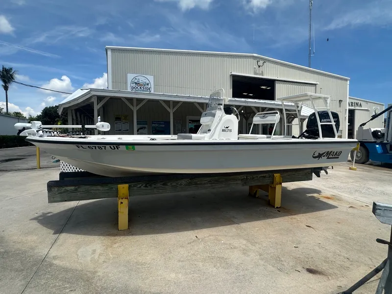 The Image of A white 2024 Mako 18 LTS boat is on a stand in front of a building. - 1