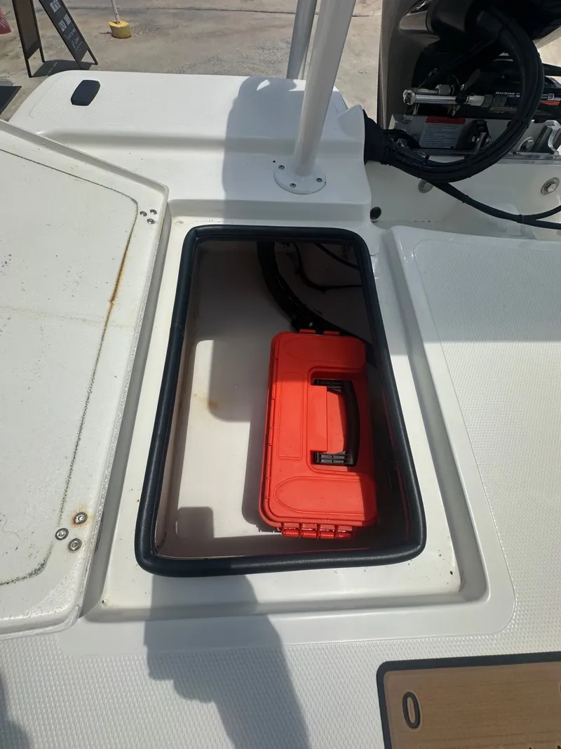 Slide: The Image of An open storage compartment on a Mako 18 LTS boat with an orange toolbox inside. - 17