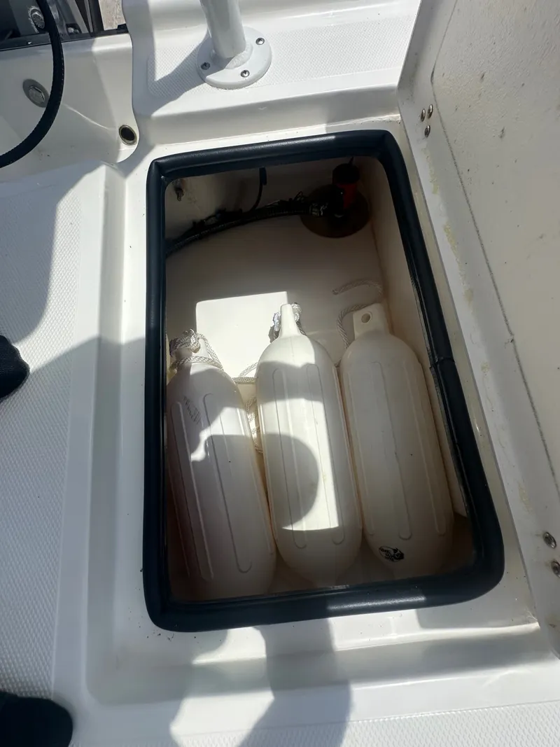 Slide: The Image of An open storage compartment on a Mako 18 LTS boat, containing fenders and equipment. - 16
