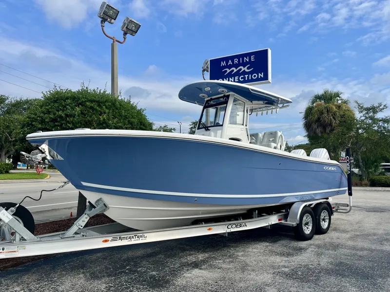 Slide: The Image of A 2027 Cobia 265 Center Console boat on a trailer in a parking lot. - 2
