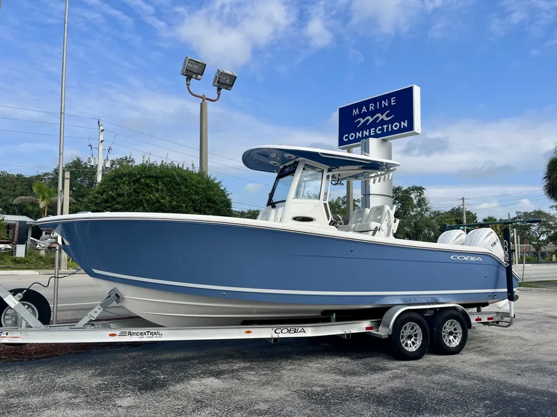 The Image of A 2027 Cobia 265 Center Console boat on a trailer in front of a dealership. - 1