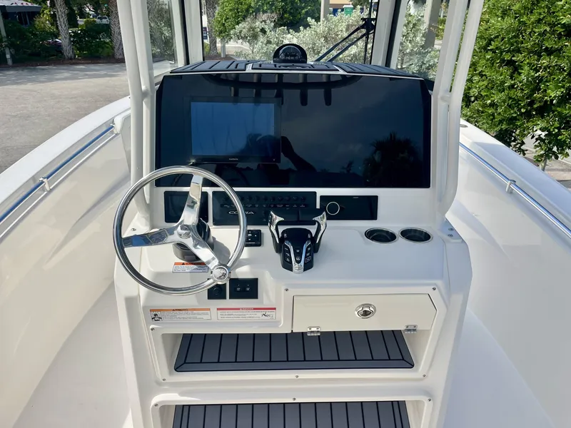 Slide: The Image of The image shows the helm of a Cobia 265 Center Console boat. It features a modern design with a large screen, steering wheel, and controls. The flooring is non-slip. - 16