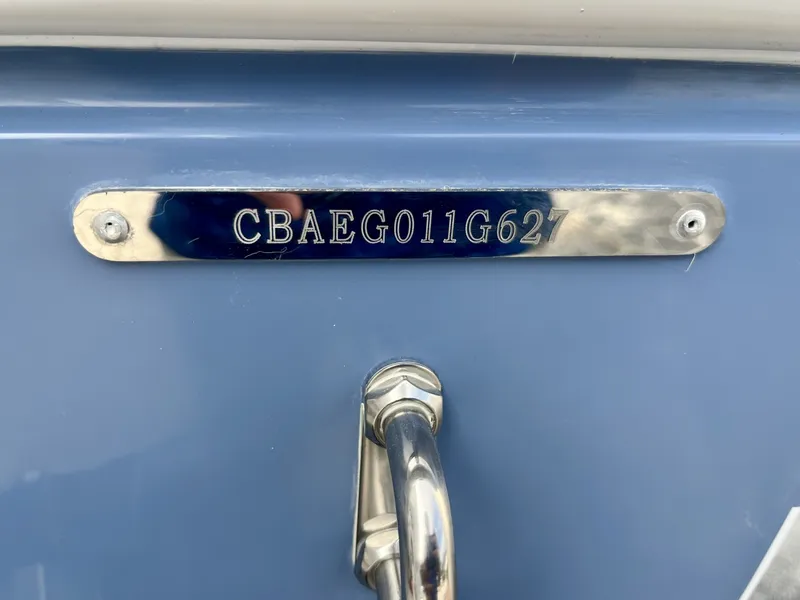 Slide: The Image of Close-up of a blue boat hull plate with serial number and metal handle. - 8