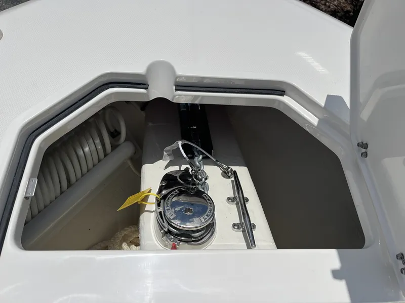 Slide: The Image of An open storage compartment on a Cobia 265 Center Console boat reveals a windlass and rope. - 25