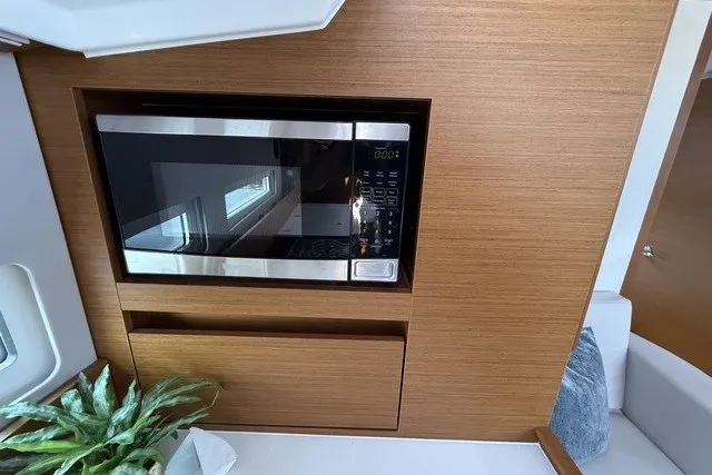 Slide: The Image of Microwave in 2022 Jeanneau Sun Odyssey 410 yacht interior, featuring sleek wood paneling. - 42