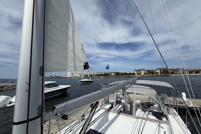 Slide: The Image of 2022 Jeanneau Sun Odyssey 410 sailboat docked, with sails partially raised, under a blue sky. - 27