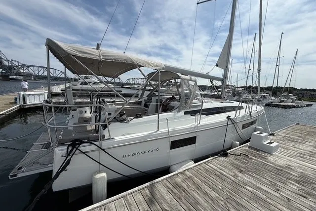 Slide: The Image of 2022 Jeanneau Sun Odyssey 410 sailboat docked at a marina under a clear sky. - 4
