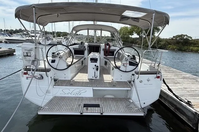 Slide: The Image of 2022 Jeanneau Sun Odyssey 410 sailboat docked, featuring dual steering wheels and spacious cockpit. - 5