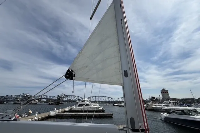 Slide: The Image of 2022 Jeanneau Sun Odyssey 410 sailboat docked at marina with bridge and cloudy sky. - 28