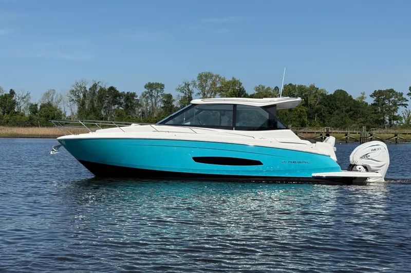 The Image of 2023 Regal 36 XO boat on calm water, featuring sleek design and vibrant blue hull. - 0