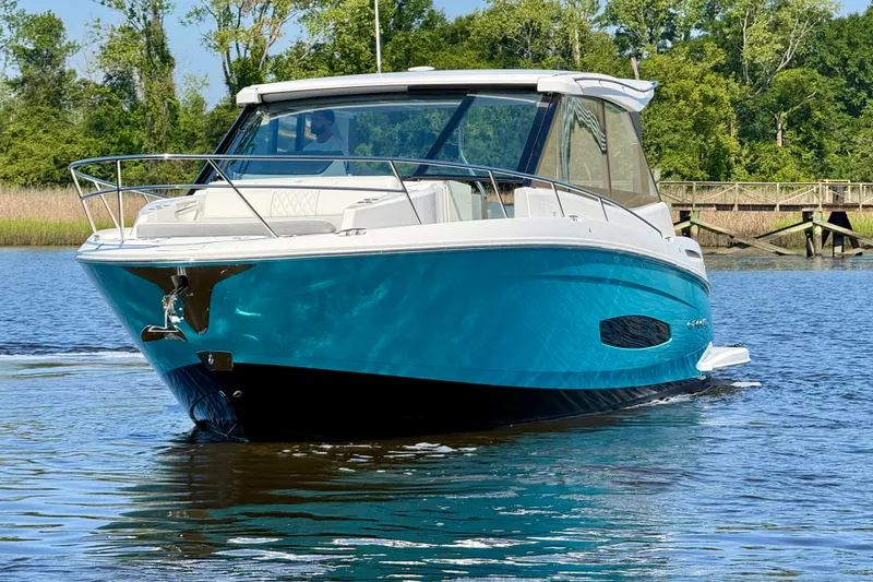 Slide: The Image of 2023 Regal 36 XO boat cruising on a serene lake with lush greenery. - 9