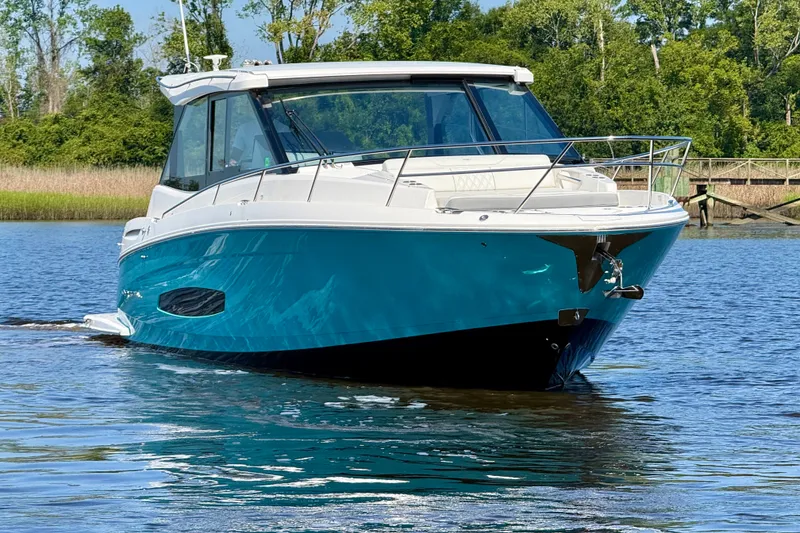 Slide: The Image of 2023 Regal 36 XO boat cruising on a serene lake with lush greenery. - 8