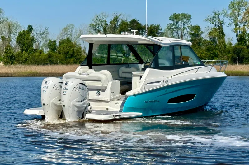 Slide: The Image of 2023 Regal 36 XO boat cruising on a serene lake with twin Yamaha engines. - 4