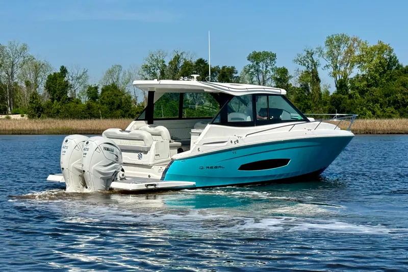 Slide: The Image of 2023 Regal 36 XO boat cruising on a serene lake with twin Yamaha engines. - 5