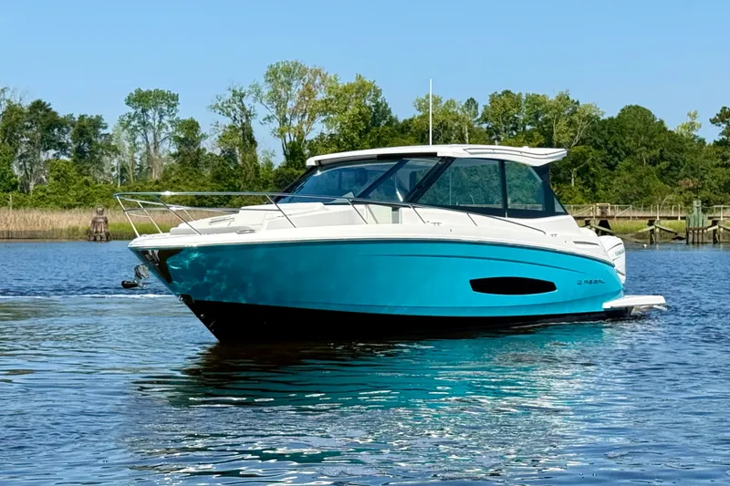 Slide: The Image of 2023 Regal 36 XO boat on calm water, surrounded by lush greenery. - 10