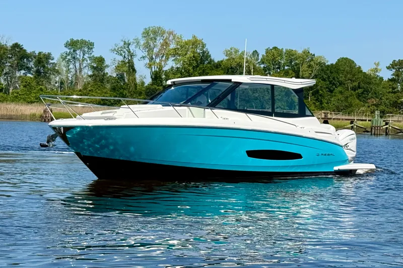 Slide: The Image of 2023 Regal 36 XO boat on calm water, surrounded by lush greenery. - 11