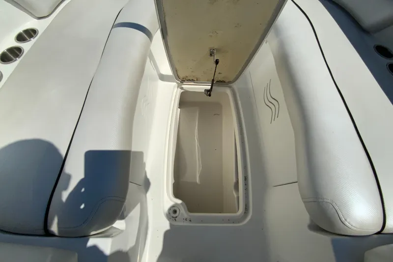 Slide: The Image of 2013 Hurricane SunDeck 2400 OB boat interior storage compartment with white cushioned seating. - 29