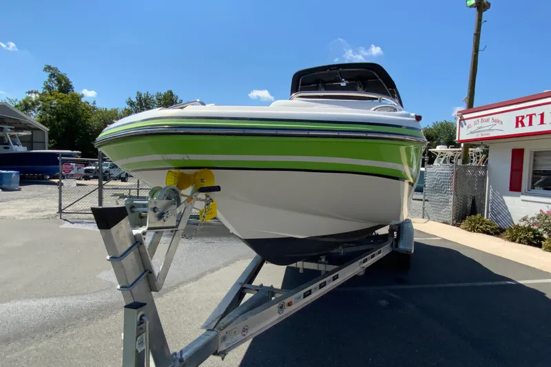 Slide: The Image of 2013 Hurricane SunDeck 2400 OB boat on trailer, vibrant green stripe, sunny day. - 5