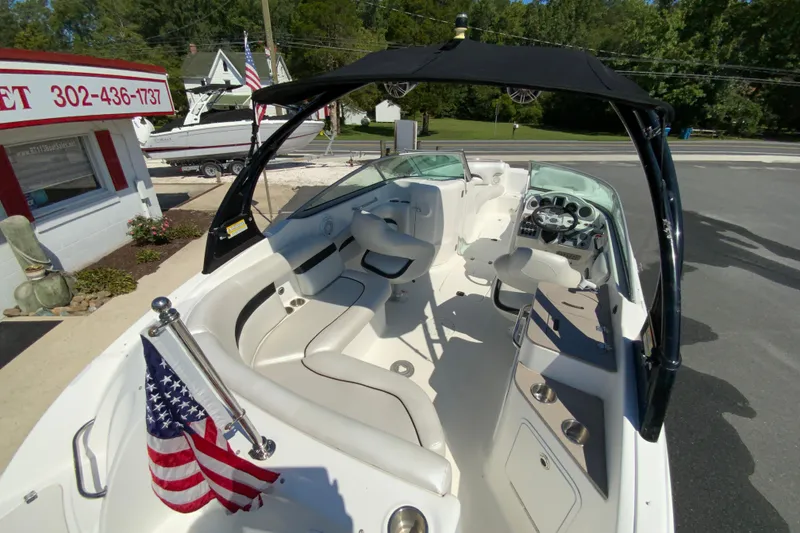 Slide: The Image of 2013 Hurricane SunDeck 2400 OB boat with American flag, parked near a dealership. - 11
