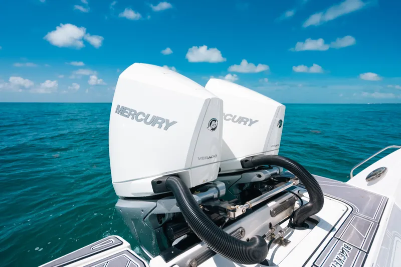 Slide: The Image of Twin Mercury outboard engines on a 2023 Blackfin 272 CC boat, cruising in clear blue waters. - 53