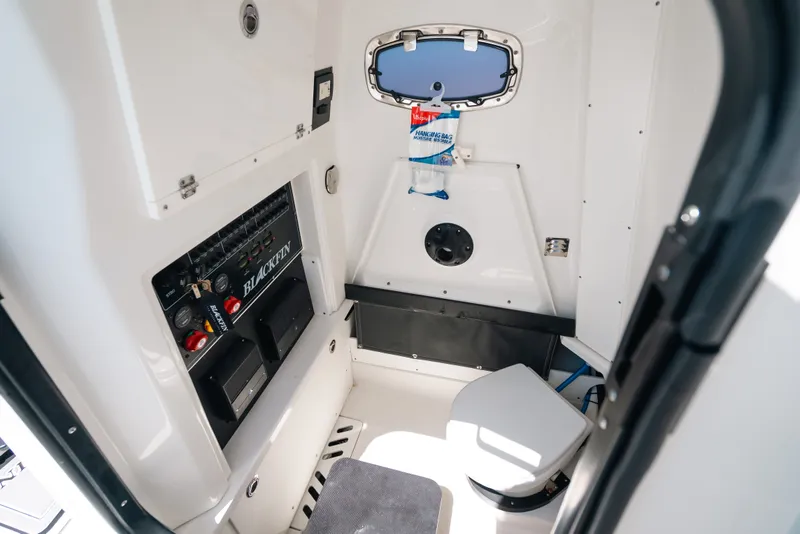 Slide: The Image of Interior of 2023 Blackfin 272 CC boat, featuring a compact marine toilet and control panel. - 49