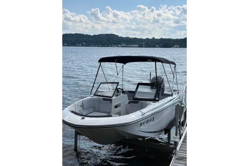 Slide: The Image of 2024 Bayliner Element M17 boat docked on a serene lake under a cloudy sky. - 7