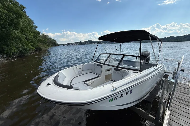 Slide: The Image of 2024 Bayliner Element M17 boat docked by a scenic lake under a clear sky. - 6