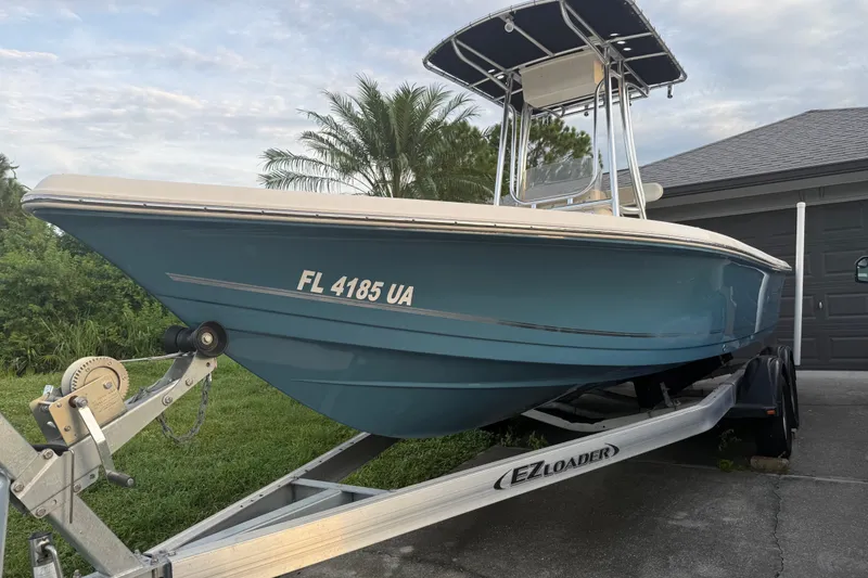 Slide: The Image of 2025 Bulls Bay 2200 XS boat on trailer, parked near garage, with lush greenery background. - 4