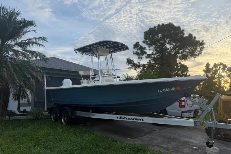 The Image of 2025 Bulls Bay 2200 XS boat on trailer, parked beside a house with palm trees. - 0