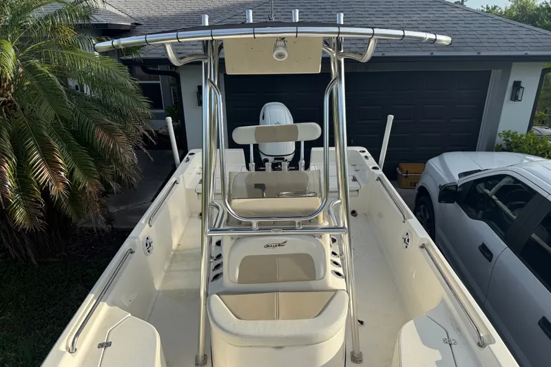 Slide: The Image of 2025 Bulls Bay 2200 XS boat with T-top and seating, parked near a house. - 24
