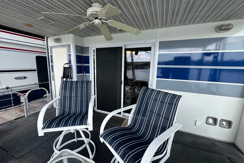 Slide: The Image of Outdoor seating area on a 1999 Sumerset 16x75 houseboat with striped chairs and ceiling fan. - 13