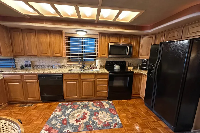 Slide: The Image of Kitchen interior of a 1999 Sumerset 16x75 houseboat with wooden cabinets and modern appliances. - 4