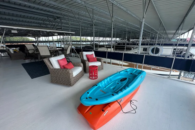 Slide: The Image of Covered dock with wicker chairs, kayak, and Sumerset 16x75 houseboat, 1999 model. - 16