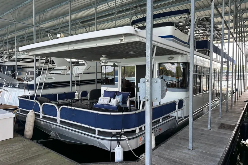 The Image of 1999 Sumerset 16x75 houseboat docked, featuring spacious deck with seating and canopy. - 0