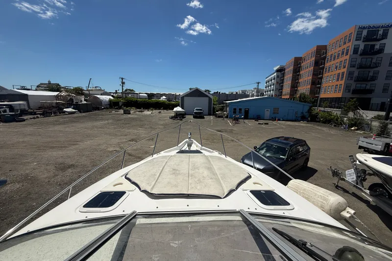 Slide: The Image of 2003 Regal Commodore 2860 boat in a marina with buildings and vehicles nearby. - 7