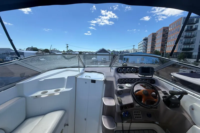 Slide: The Image of 2003 Regal Commodore 2860 boat cockpit with steering wheel and control panel under clear blue sky. - 5
