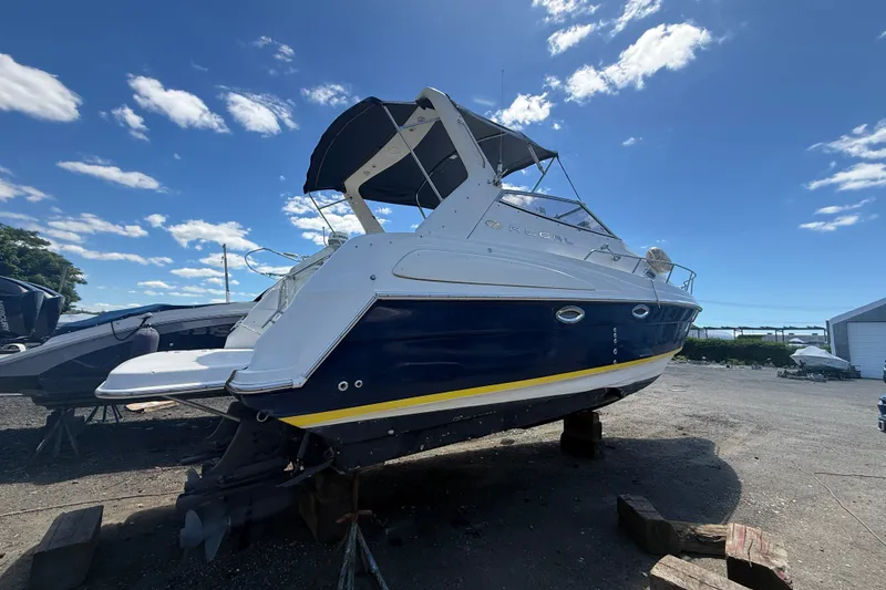 Slide: The Image of 2003 Regal Commodore 2860 boat on dry dock under a clear blue sky. - 1