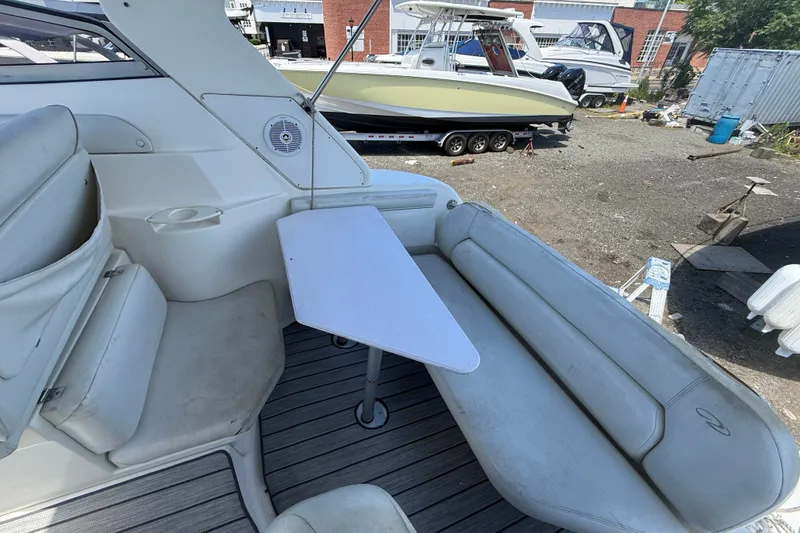 Slide: The Image of 2003 Regal Commodore 2860 boat interior with seating and table, docked near other boats. - 2