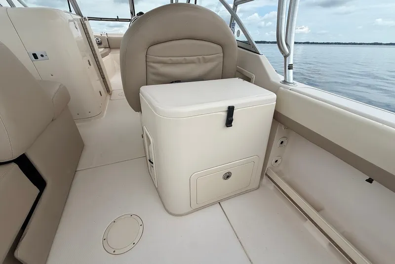 Slide: The Image of 2013 Grady-White Freedom 275 boat interior with seating and storage, on calm water. - 17